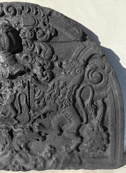A semicircular cast iron fireplace plaque, decorated with a coat of arms, surmounted by a helmet and framed by lions. A semicircular cast iron fireplace plaque, decorated with a coat of arms, surmounted by a helmet and framed by lions.-5