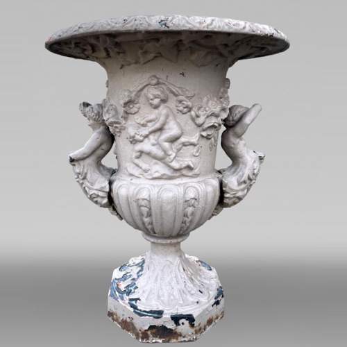 Cast iron garden vase with a frieze of cupids and handles formed as winged putti